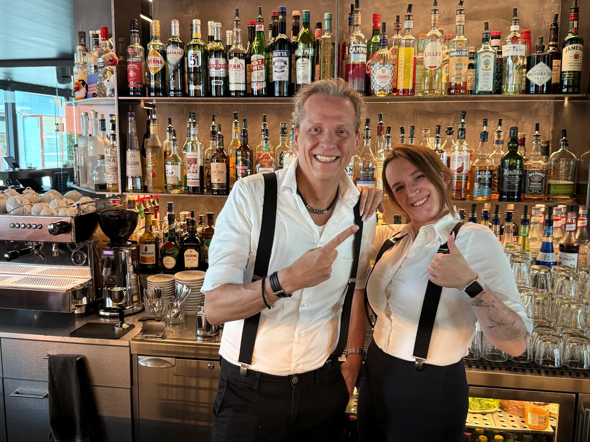 noneBar-Inhaber Oliver Brand und die stellvertretende Barchefin Martina Kaschel mixen im «My Senses» Drinks aus einer Karte, die fast so dick wie ein Buch ist. Zwei Barkeeper in einer Bar mit Flaschen im Hintergrund.